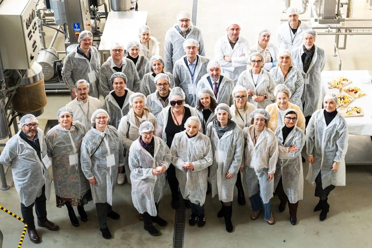 Grupa uczestników projektu Living Labs w odzieży ochronnej na hali laboratoryjnej.