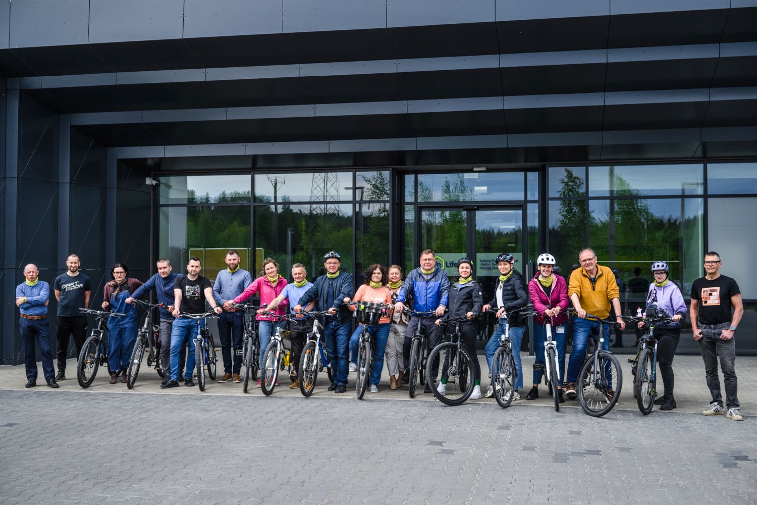 Grupa uczestników akcji Bike2InLife stojących z rowerami przed budynkiem instytutu.