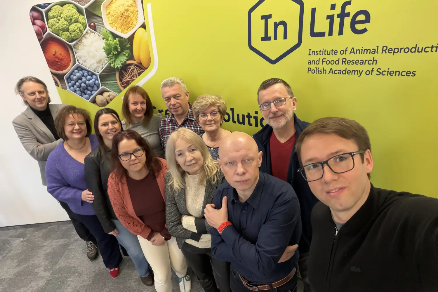 Grupa naukowców na pamiątkowym zdjęciu na tle ścianki InLife PAN podczas seminarium naukowego.