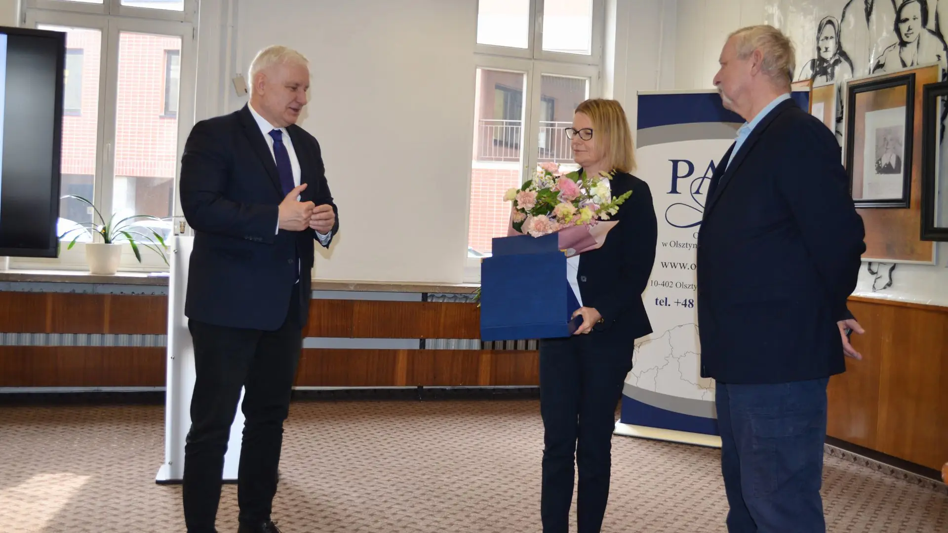 Prof. Mariola Dietrich z bukietem kwiatów i nagrodą w otoczeniu przedstawicieli Oddziału PAN.