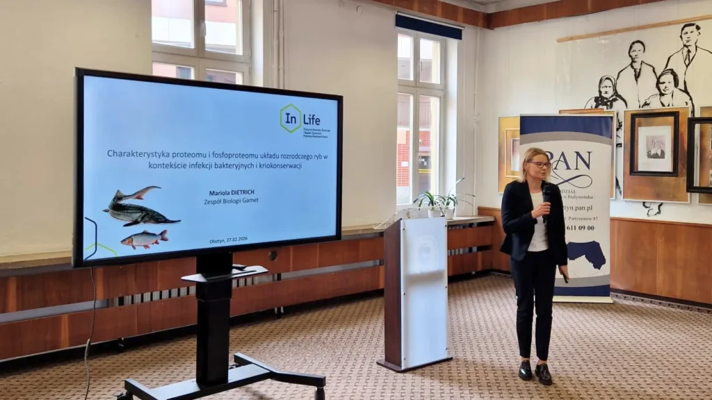 Prof. Mariola Dietrich prowadząca wykład obok ekranu z tytułem swojej prezentacji naukowej.
